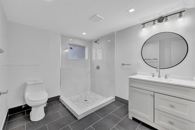 bathroom with toilet, vanity, tile patterned floors, and tiled shower