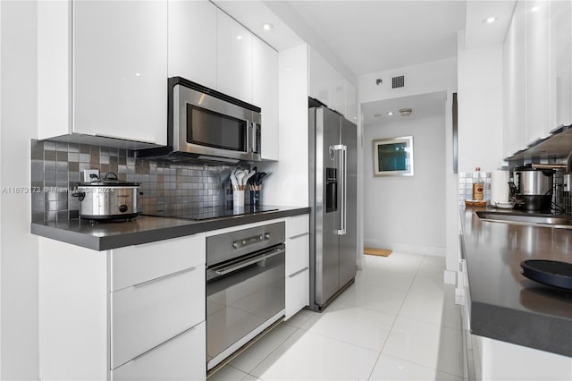 kitchen featuring black appliances, light tile patterned flooring, white cabinetry, and tasteful backsplash