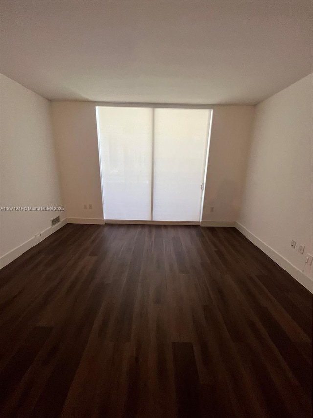 spare room with dark wood-type flooring and a wall of windows