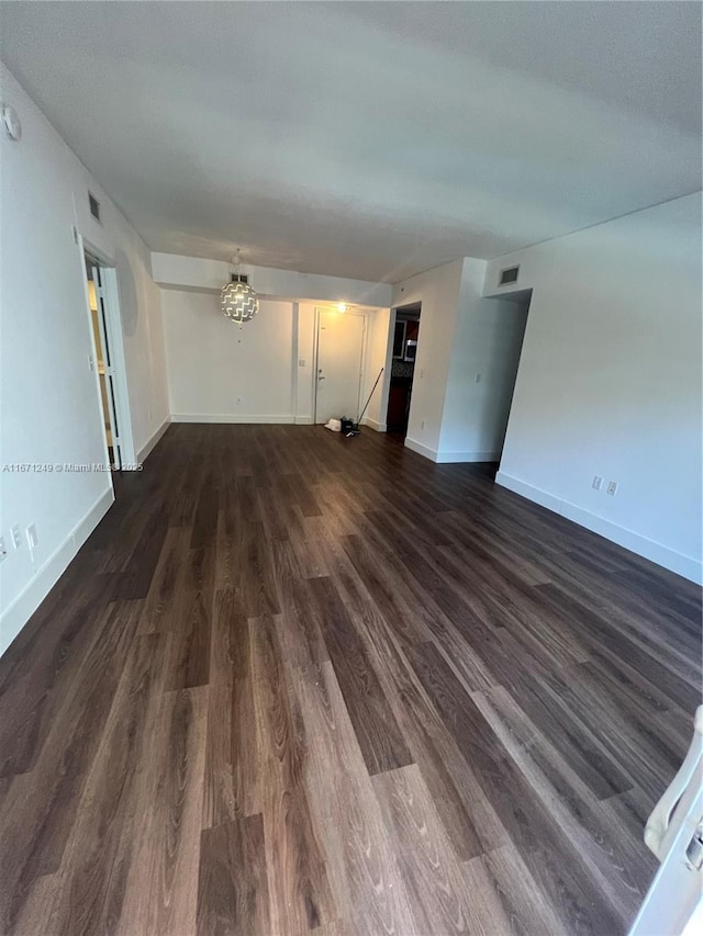 unfurnished living room featuring dark hardwood / wood-style flooring and a notable chandelier