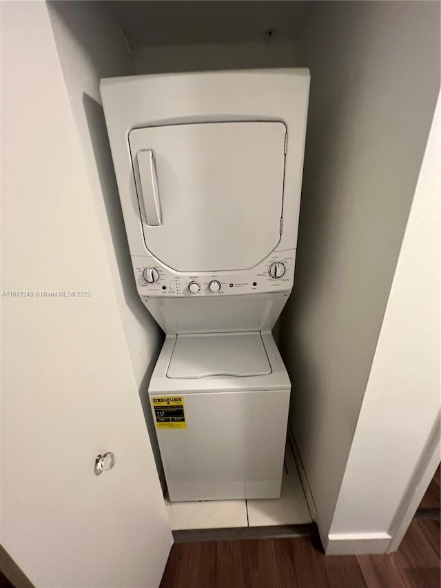 laundry room featuring stacked washing maching and dryer and dark hardwood / wood-style floors