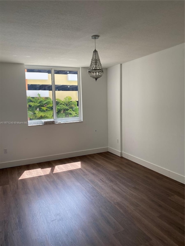 spare room with a textured ceiling and dark hardwood / wood-style flooring