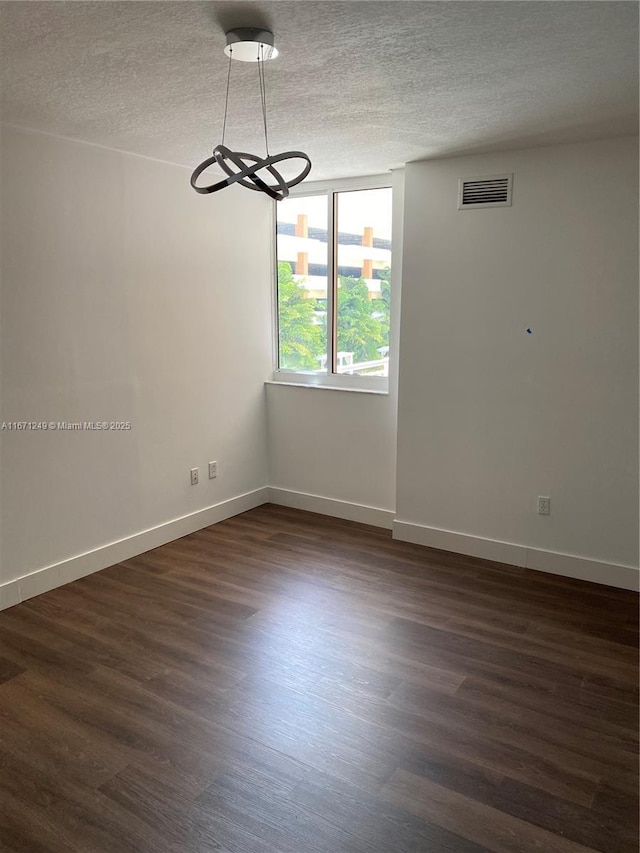 unfurnished room featuring a textured ceiling and dark hardwood / wood-style floors