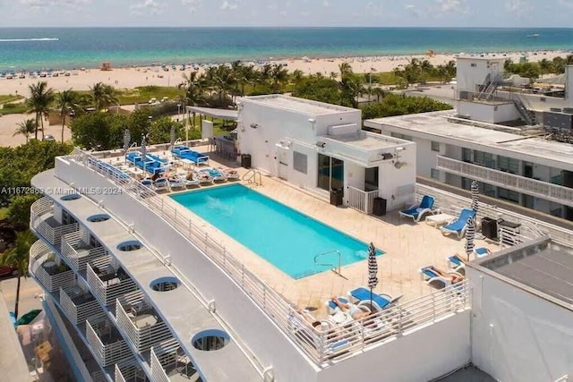 view of pool with a patio, a water view, and a beach view