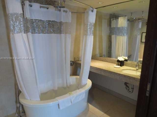 full bathroom featuring sink, shower / bath combo with shower curtain, toilet, and tile patterned flooring