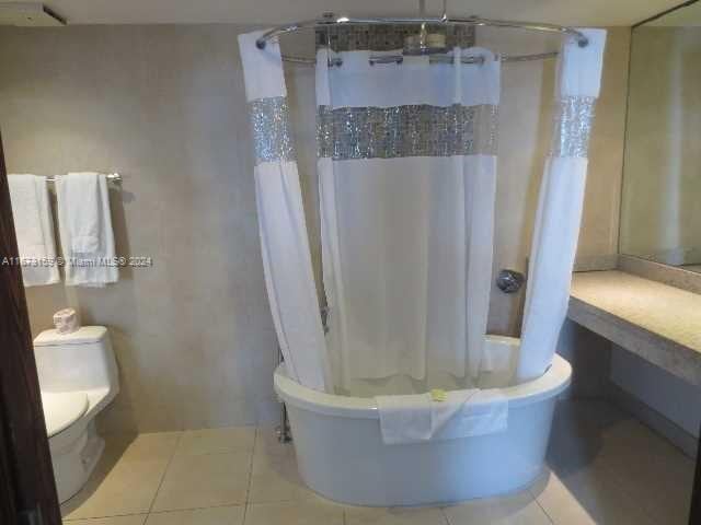 bathroom with tile patterned floors, shower / tub combo, and toilet