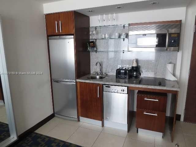 kitchen with decorative backsplash, sink, light tile patterned floors, and stainless steel appliances