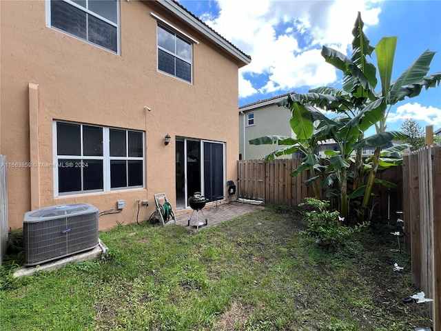 rear view of house with a lawn, a patio, and central AC