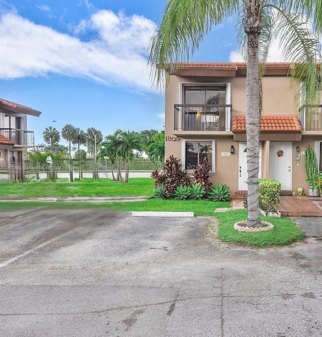 view of front of home with a balcony and a front lawn