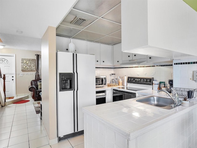 kitchen with kitchen peninsula, white refrigerator with ice dispenser, sink, and electric range