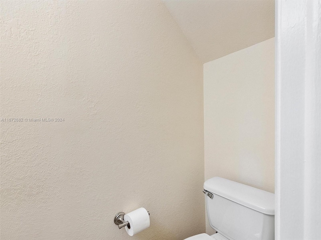 bathroom with lofted ceiling and toilet