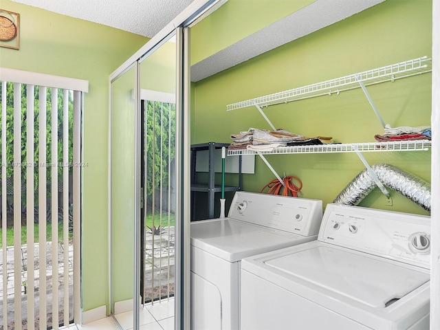 laundry room with washing machine and dryer, light tile patterned floors, and a textured ceiling