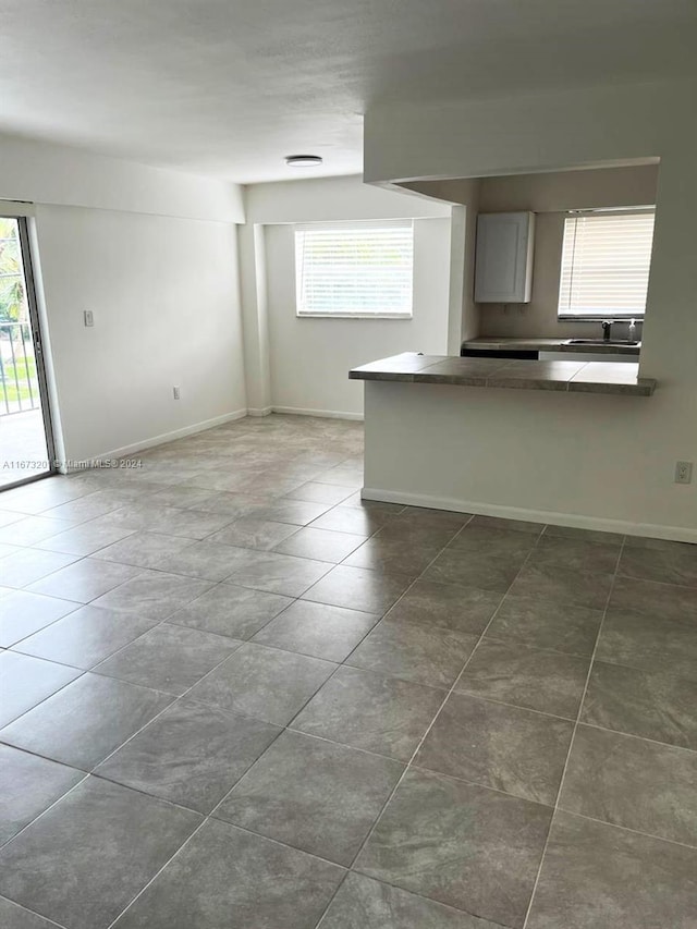 kitchen with dark tile patterned floors, kitchen peninsula, and sink