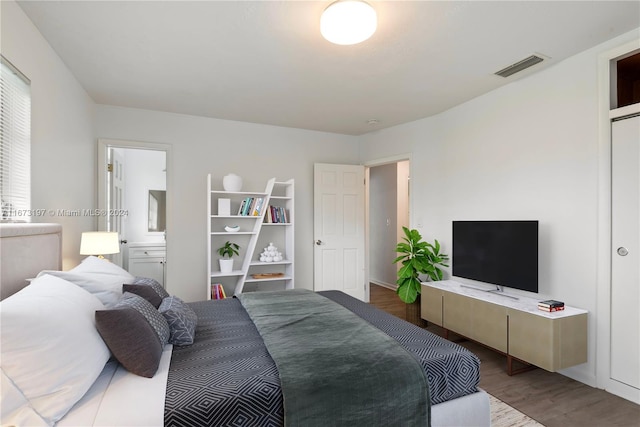 bedroom featuring connected bathroom and wood-type flooring