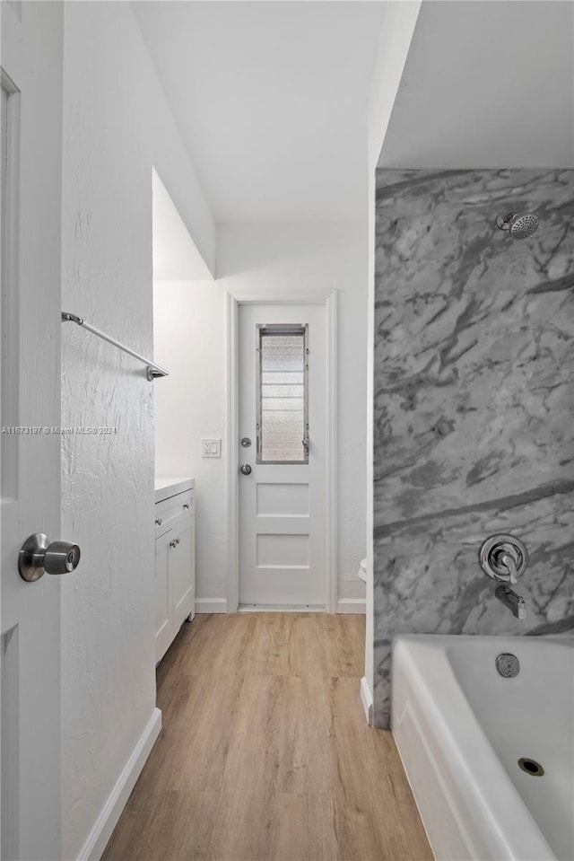 bathroom with bathtub / shower combination, vanity, and hardwood / wood-style flooring