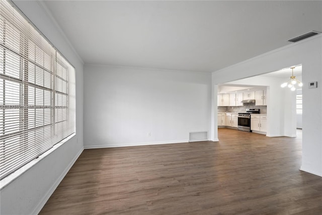 unfurnished living room with crown molding, dark wood-type flooring, and a notable chandelier