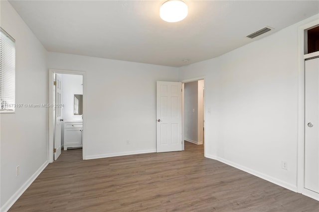 unfurnished bedroom featuring dark hardwood / wood-style floors and connected bathroom