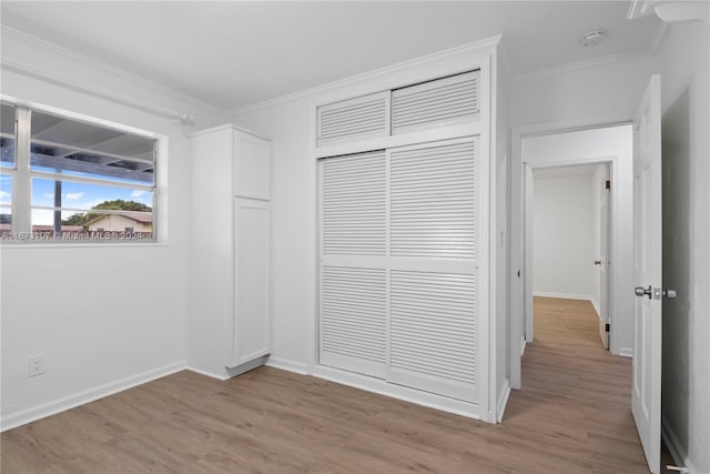 unfurnished bedroom featuring a closet, ornamental molding, and light hardwood / wood-style flooring