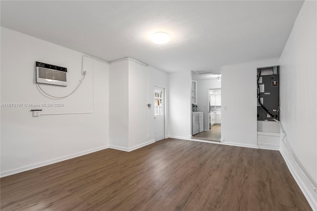 spare room with a wall mounted AC, washer / clothes dryer, heating unit, and dark wood-type flooring