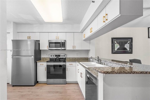 kitchen featuring kitchen peninsula, white cabinetry, and appliances with stainless steel finishes