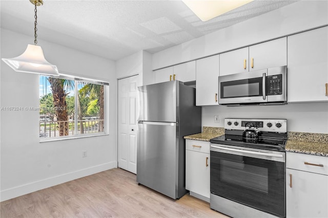 kitchen with light hardwood / wood-style flooring, dark stone countertops, decorative light fixtures, white cabinetry, and stainless steel appliances