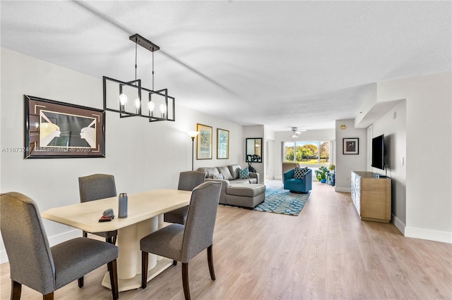 dining room featuring a textured ceiling, ceiling fan with notable chandelier, and light wood-type flooring