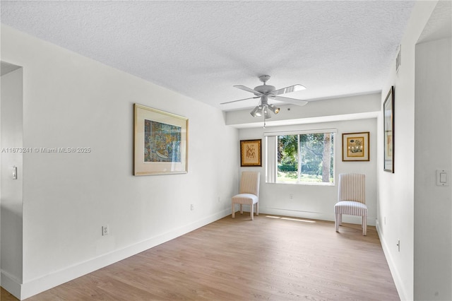 unfurnished room featuring ceiling fan, light hardwood / wood-style flooring, and a textured ceiling