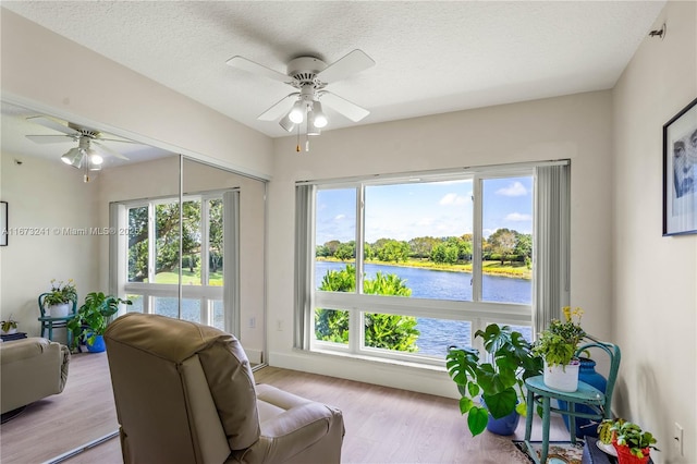 interior space with ceiling fan, a healthy amount of sunlight, a water view, and a textured ceiling