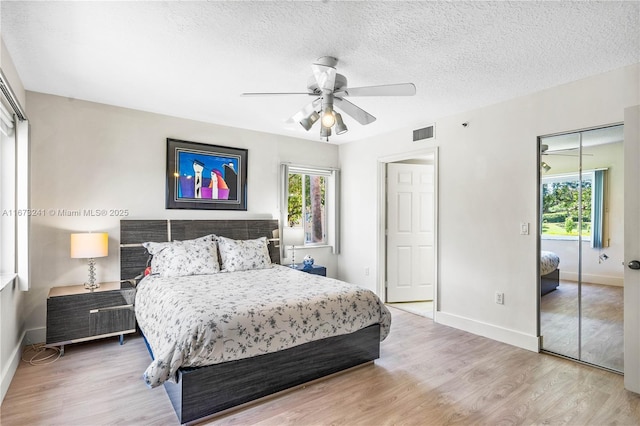 bedroom featuring multiple windows, a textured ceiling, hardwood / wood-style flooring, and ceiling fan