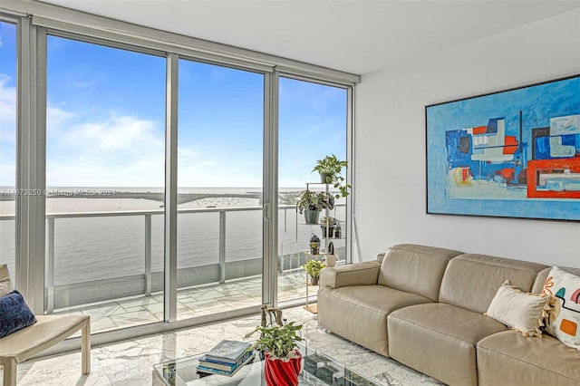 living room featuring a wealth of natural light, a water view, and a wall of windows