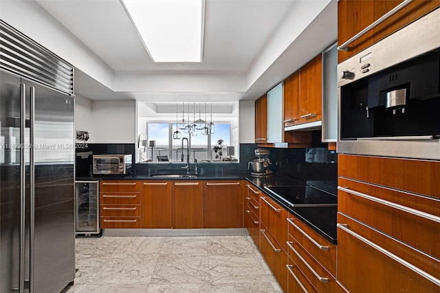 kitchen featuring pendant lighting, wine cooler, sink, appliances with stainless steel finishes, and a notable chandelier