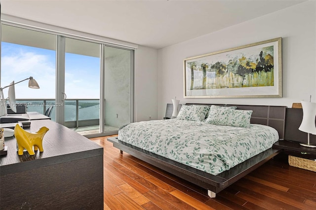 bedroom with access to outside, a wall of windows, and hardwood / wood-style floors