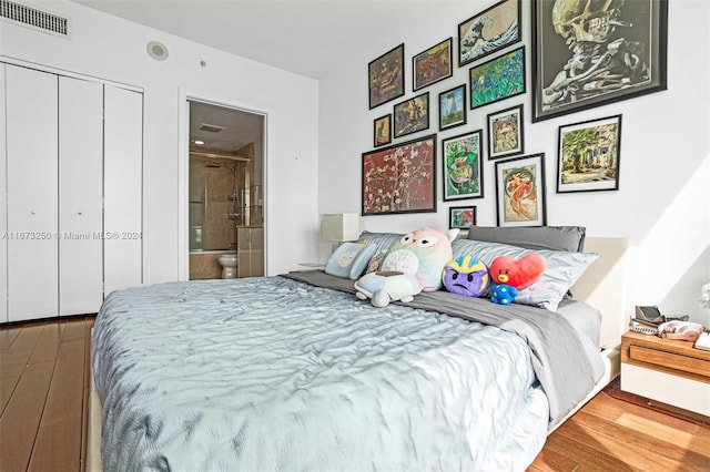 bedroom featuring wood-type flooring, a closet, and ensuite bath