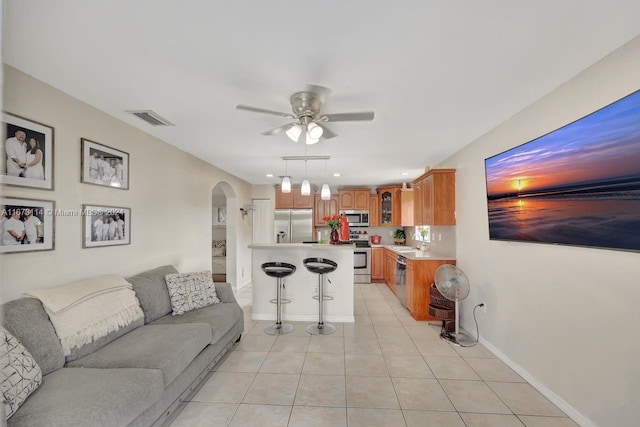 living room featuring sink, ceiling fan, and light tile patterned floors