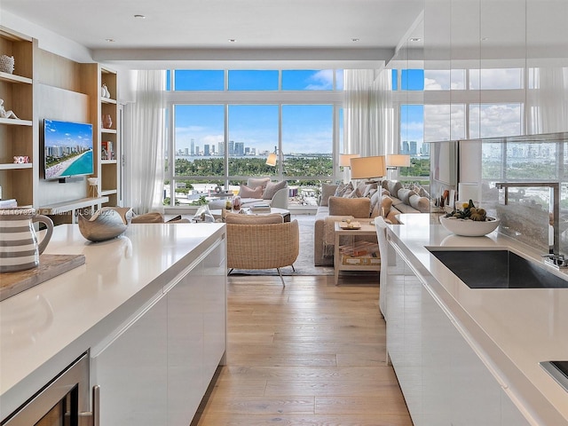 kitchen featuring wine cooler, light hardwood / wood-style floors, sink, and white cabinetry