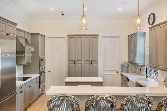 kitchen with wall chimney exhaust hood, hanging light fixtures, black electric stovetop, and a kitchen breakfast bar