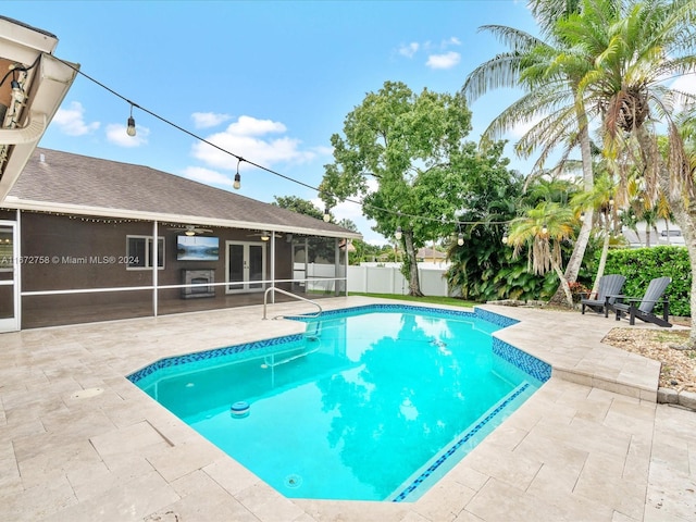 view of pool with a sunroom and a patio area