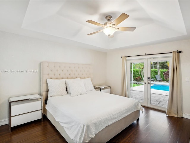 bedroom with ceiling fan, a raised ceiling, french doors, access to exterior, and dark hardwood / wood-style flooring