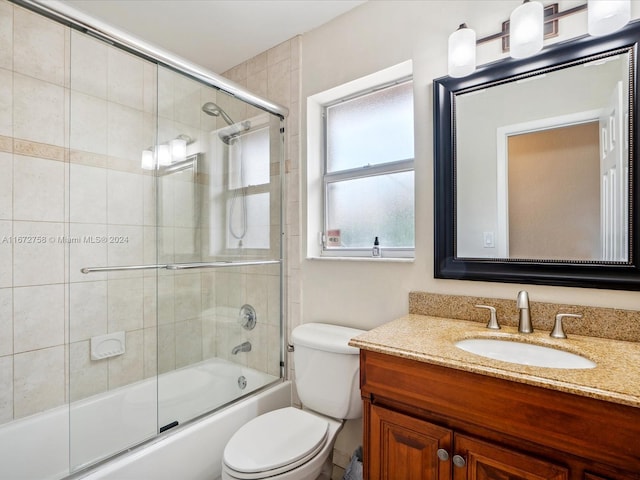 full bathroom featuring combined bath / shower with glass door, vanity, and toilet