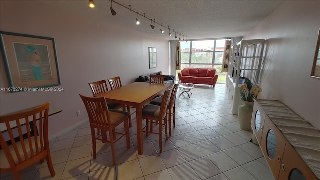 dining room featuring rail lighting, light tile patterned flooring, and a wall of windows