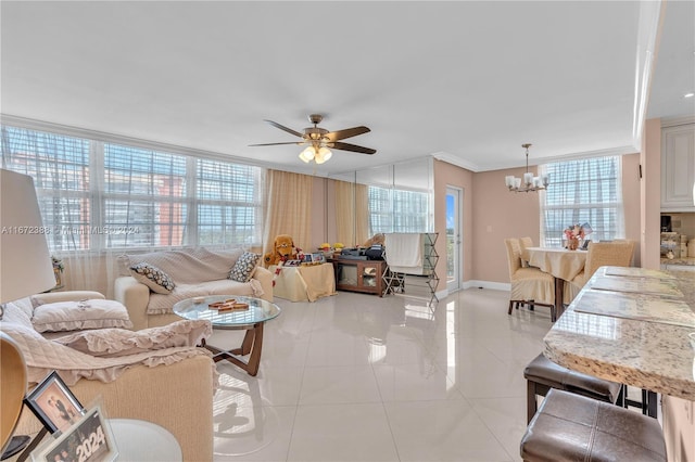 living room with light tile patterned flooring, ceiling fan with notable chandelier, crown molding, and a healthy amount of sunlight