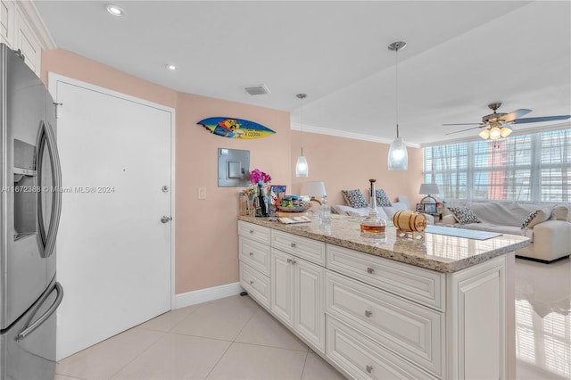 kitchen with hanging light fixtures, stainless steel fridge, white cabinetry, light stone counters, and ceiling fan