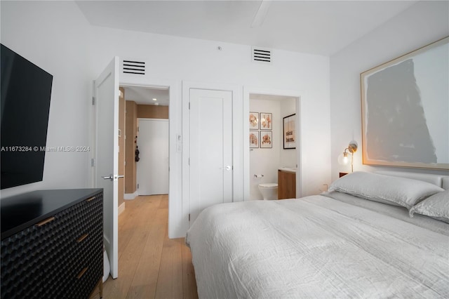 bedroom with ensuite bath and light hardwood / wood-style flooring