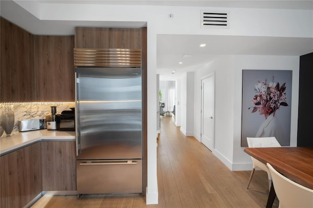 kitchen featuring decorative backsplash, light hardwood / wood-style floors, and built in refrigerator