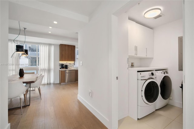 clothes washing area featuring independent washer and dryer, electric panel, cabinets, and light wood-type flooring