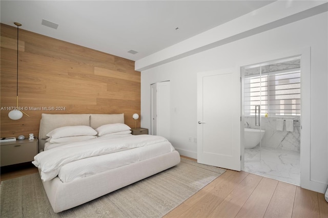 bedroom featuring hardwood / wood-style flooring, ensuite bath, and wood walls