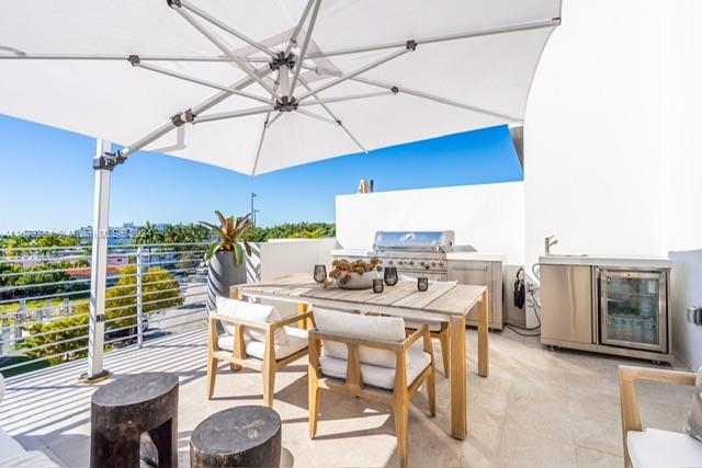 view of patio featuring exterior kitchen, area for grilling, and a balcony