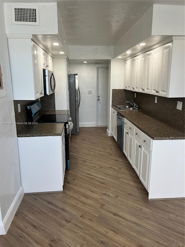 kitchen featuring sink, backsplash, dark wood-type flooring, white cabinetry, and stainless steel appliances