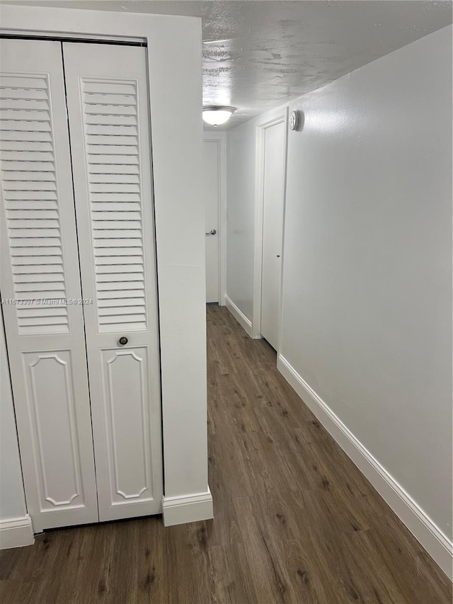 100 Golden Isles Dr Unit 605, Hallandale Beach, FL 33009 - corridor featuring dark wood-type flooring, baseboards, and a textured ceiling