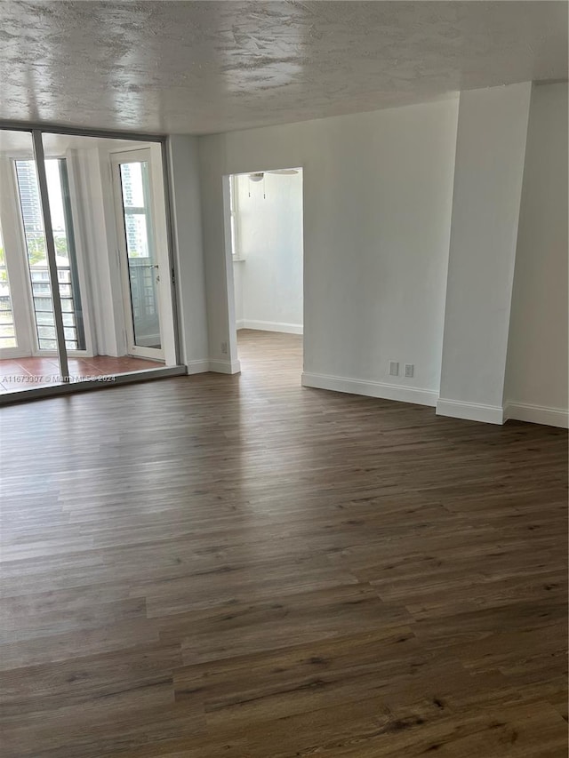 spare room with a textured ceiling and dark hardwood / wood-style flooring